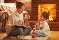 family mother and child reading book on winter evening by fireplace.