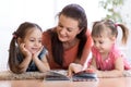 Cute mother and children daughters lie on floor and read book together