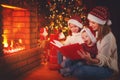 Family mother and children read a book at christmas near fire Royalty Free Stock Photo
