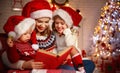 Family mother and children read a book at christmas near firep Royalty Free Stock Photo