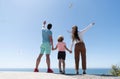 family of mother dad and child boy looking in future holding hands in summer, back view, charity