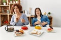 Family of mother and down syndrome daughter sitting at home eating breakfast disgusted expression, displeased and fearful doing Royalty Free Stock Photo