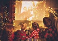 Family mother father and children watching projector, TV, movies with popcorn in   christmas evening   at home Royalty Free Stock Photo