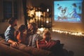 Family mother father and children watching projector, TV, movies with popcorn in   evening   at home Royalty Free Stock Photo