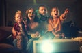 Family mother father and children watching projector, TV, movies with popcorn in evening at home