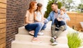 Family with a mother, father son and daughter sitting outside on the steps of a front porch of a brick house Royalty Free Stock Photo