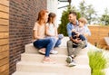 Family with a mother, father son and daughter sitting outside on the steps of a front porch of a brick house Royalty Free Stock Photo