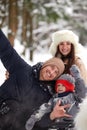 Family of mother, father and son having fun in snowy winter wood with cheerfull pet dog. Royalty Free Stock Photo