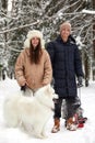 Family of mother, father and son having fun in snowy winter wood with cheerfull pet dog. Royalty Free Stock Photo