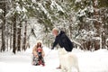 Family of mother, father and son having fun in snowy winter wood with cheerfull pet dog. Royalty Free Stock Photo