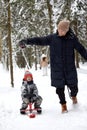 Family of mother, father and son having fun in snowy winter wood with cheerfull pet dog. Royalty Free Stock Photo