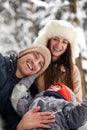 Family of mother, father and son having fun in snowy winter wood with cheerfull pet dog. Royalty Free Stock Photo