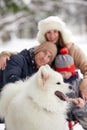 Family of mother, father and son having fun in snowy winter wood with cheerfull pet dog. Royalty Free Stock Photo