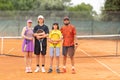 A family of mother and father and their two sons stand on a tennis court holding rackets Royalty Free Stock Photo