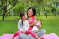 Family of mother feeding milk infant from bottle with take care her daughter lying in the garden Royalty Free Stock Photo