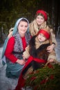 Family with mother, teenage girl, and little daughter dressed in stylized medieval peasant clothing in winter forest