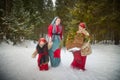 Family with mother, teenage girl, and little daughter dressed in stylized medieval peasant clothing in winter forest