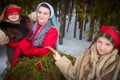 Family with mother, teenage girl, and little daughter dressed in stylized medieval peasant clothing in winter forest