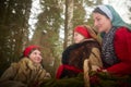 Family with mother, teenage girl, and little daughter dressed in stylized medieval peasant clothing in winter forest