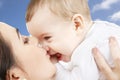 Mother kissing baby over sky background Royalty Free Stock Photo