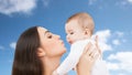 Mother kissing baby over sky background Royalty Free Stock Photo