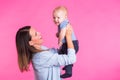 Family, motherhood, parenting, people and child care concept - happy mother holds adorable baby over pink background Royalty Free Stock Photo