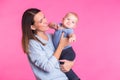 Family, motherhood, parenting, people and child care concept - happy mother holds adorable baby over pink background Royalty Free Stock Photo