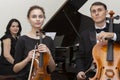 Family music trio. A young violinist and cellist play, the pianist accompanies them Royalty Free Stock Photo