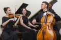 Family music trio. A young violinist and cellist play, the pianist accompanies them Royalty Free Stock Photo