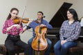 Family music trio. A young violinist and cellist play, the pianist accompanies them Royalty Free Stock Photo