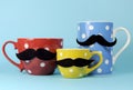 A family of mustaches on blue, red and yellow polka dot coffee and tea cups and mugs