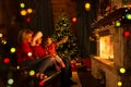 Family near fireplace and Christmas tree in festive decorated house interior Royalty Free Stock Photo