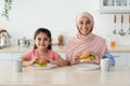Family Nutrition. Islamic Woman And Her Little Daughter Eating Sandwiches In Kitchen