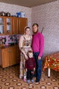 A family of Old Believers stands in a house and looks at the camera in traditional clothes