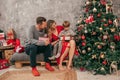 Family with one child have fun with gift box near Christmas tree on sofa, red green colors, home decoration, happy moments Royalty Free Stock Photo