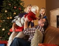 Family Opening Presents In Front Of Christmas Tree