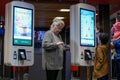 Family ordering food at self check out machine and old lady playing cellphone