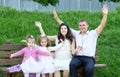Family on outdoor open arms, pregnant woman with child and man, city park, summer season, green grass and trees