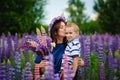 Family outdoor recreation on weekends. A happy mother and a cute baby son are hugging tightly among wild flowers in a field. Royalty Free Stock Photo