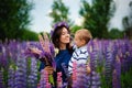 Family outdoor recreation on weekends. A happy mother and a cute baby son are hugging tightly among wild flowers in a field. Royalty Free Stock Photo
