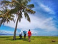 A family outing and coconut tree in the Tanjung Aru Beach, Kota Kinabalu with the beautiful blue sky above on sunny day.