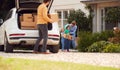 Family Outside New Home On Moving Day Unloading Boxes From Car As Son With Skateboard Helps Royalty Free Stock Photo