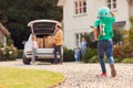 Family Outside New Home On Moving Day Unloading Boxes From Car As Son With Skateboard Runs To Help Royalty Free Stock Photo