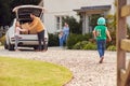 Family Outside New Home On Moving Day Unloading Boxes From Car As Son With Skateboard Runs To Help Royalty Free Stock Photo