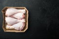 Family pack of fresh chicken legs, in paper Pack, on black stone background, top view flat lay, with copy space for text