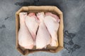Family pack of fresh chicken legs, in paper Pack, on gray stone background, top view flat lay