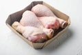 Family pack of fresh chicken legs, in paper Pack, on white stone background