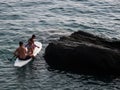 Family on a paddle surf. Dad and children sitted on a surfboard riding next to a cliff