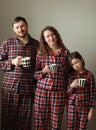 Family in pajamas on a white background. Dad, mom and little daughter with cups of tea. They smile, fool around, build