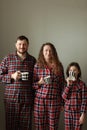 Family in pajamas on a white background. Dad, mom and little daughter with cups of tea. They smile, fool around, build funny faces